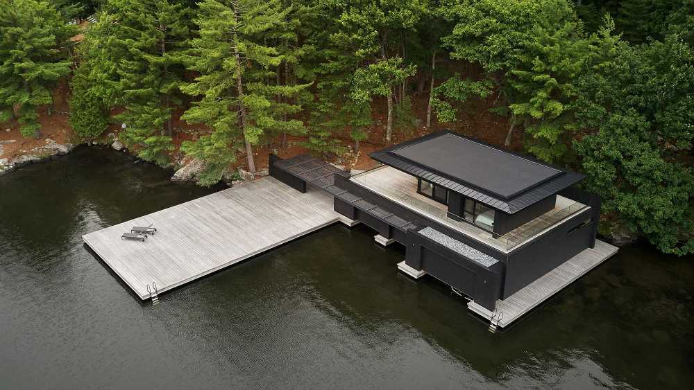 Boathouse in legno carbonizzato. Piani paralleli in legno costruiscono uno spazio etereo sulla riva del lago