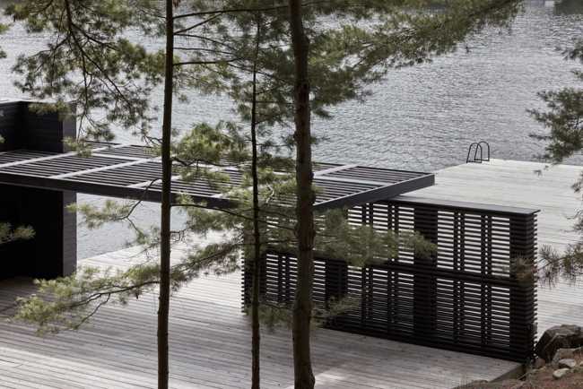 Boathouse in legno carbonizzato. Piani paralleli in legno costruiscono uno spazio etereo sulla riva del lago