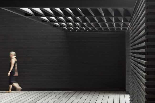 Boathouse in legno carbonizzato. Piani paralleli in legno costruiscono uno spazio etereo sulla riva del lago