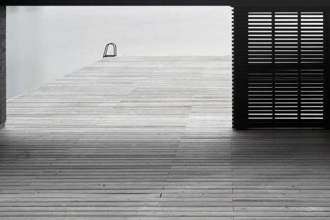 Boathouse in legno carbonizzato. Piani paralleli in legno costruiscono uno spazio etereo sulla riva del lago