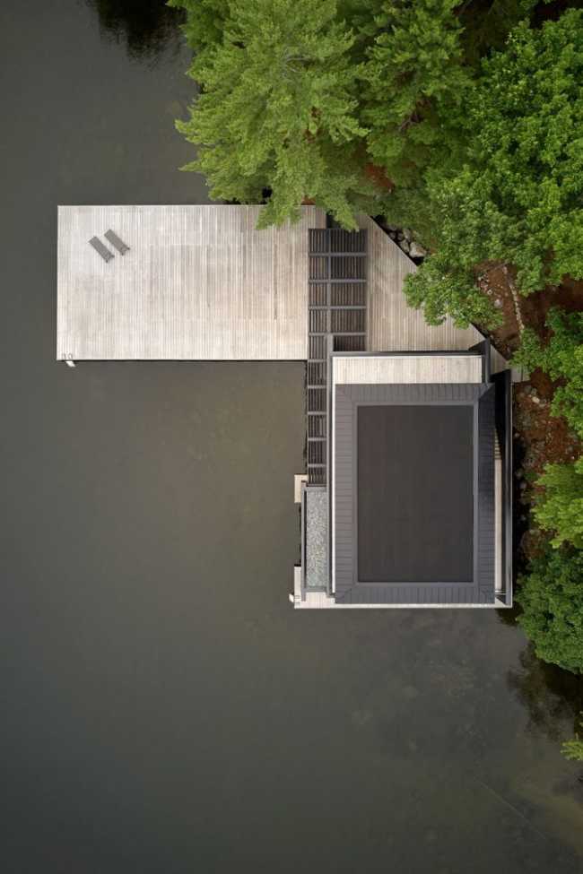 Boathouse in legno carbonizzato. Piani paralleli in legno costruiscono uno spazio etereo sulla riva del lago