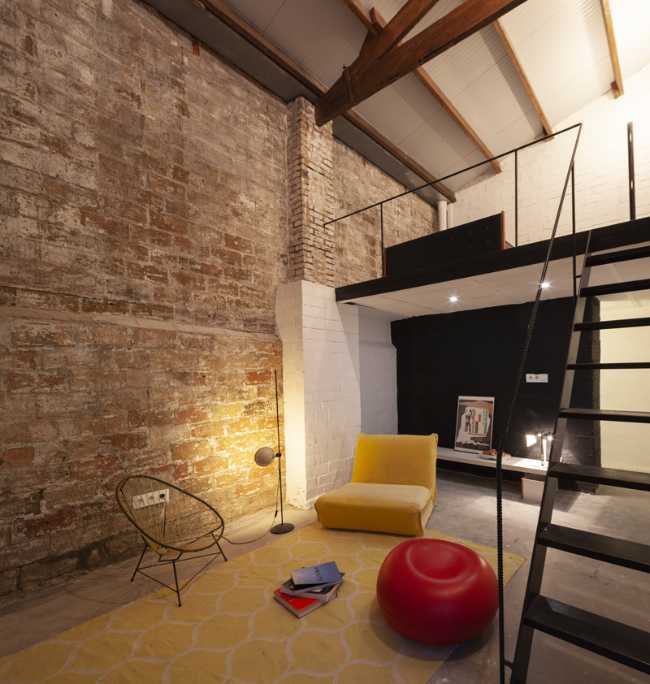 altillo con escalera de metal, pared de ladrillo y mobiliario amarillo