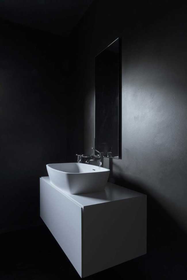 The white bathroom cabinet contrasts with the dark wall
