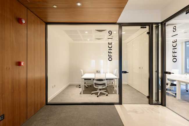 Offices with glass windows with white interiors and wood paneling