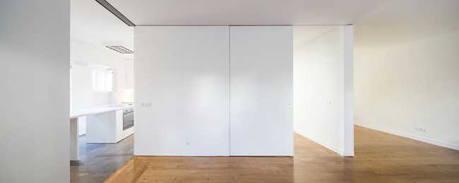 The kitchen floor in cement contrasts with the wooden floor