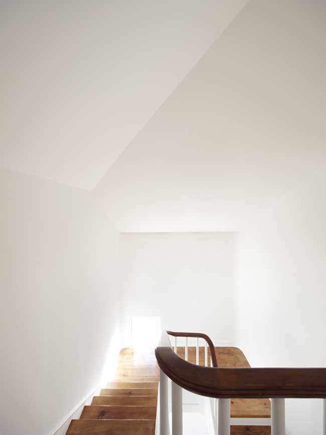 the white staircase with the finishes and the wooden handrail