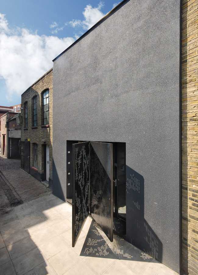 La facciata ha un rivestimento grigio in contrasto con i mattoni degli altri edifici