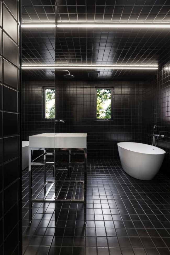 Nel bagno dalle ceramiche nere i sanitari sono bianchi