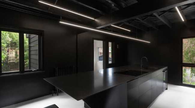 La cucina è realizzata con metallo scuro in contrasto con il pavimento bianco