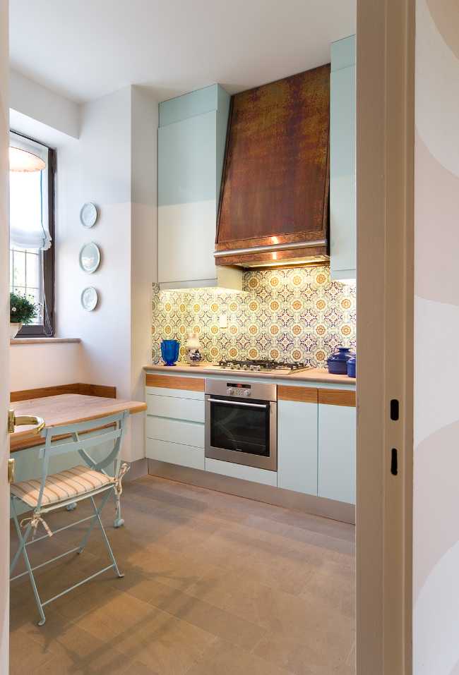 La cucina con i toni pastello e il pavimento in legno