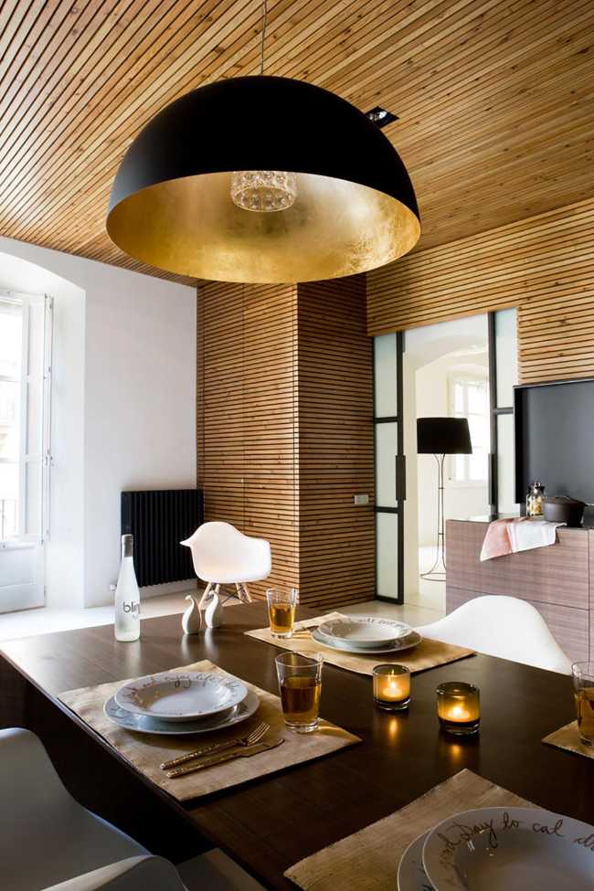 The large black and gold chandelier above the wooden dining table
