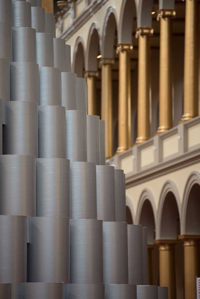 I tubi della struttura grigi in esterno si armonizzano con il grigio e oro della sala