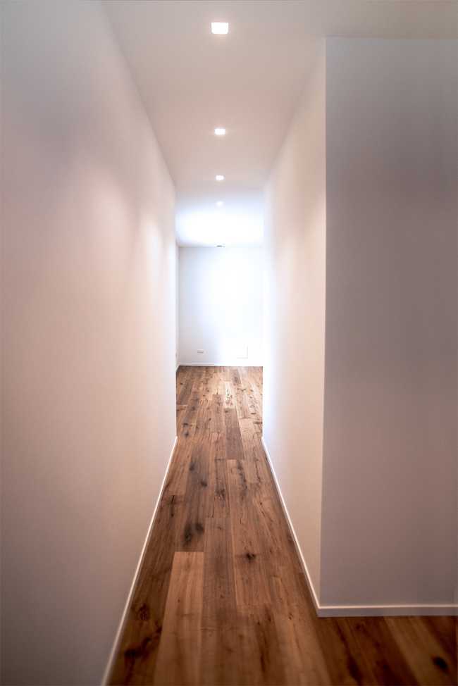 Corridoio con pavimento in legno e pareti bianche