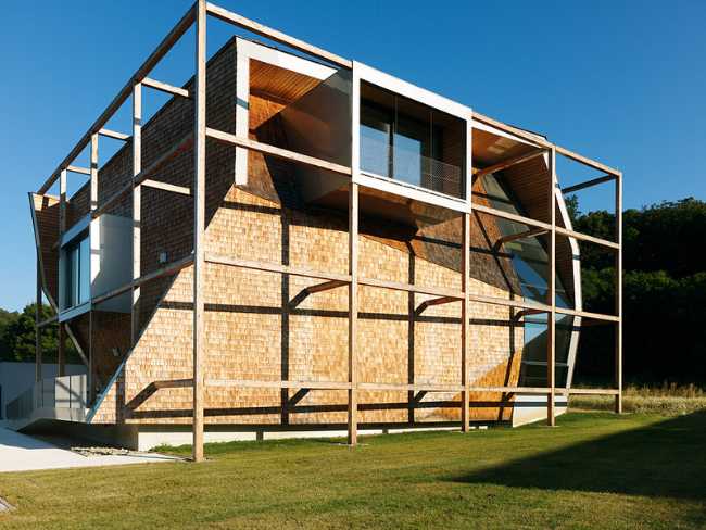 Exterior of the office building set in a green lawn with a wooden structure in sight