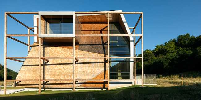 Front of the building with glass windows, exposed structure and prefabricated panels