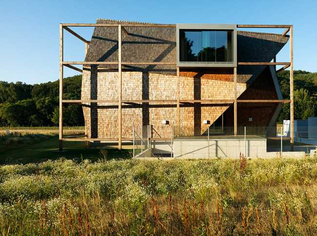 Exterior of the building with exposed wooden structure on a lawn