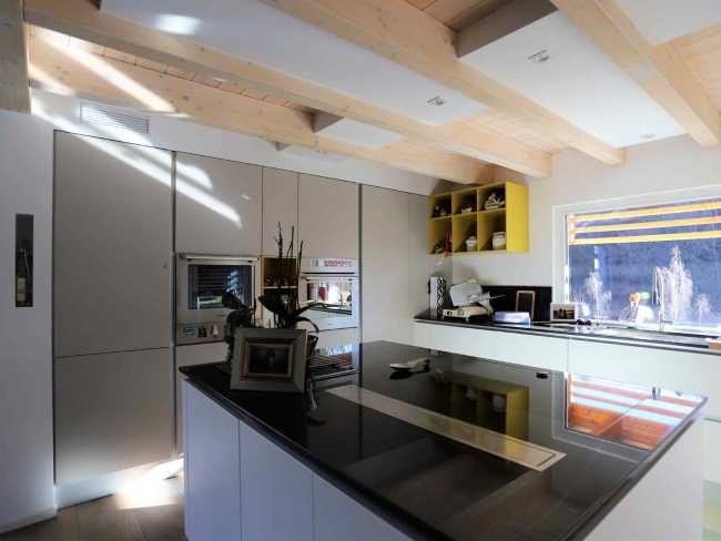 Cucina bianca con top nero in un'abitazione in legno
