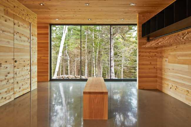 Abitazione con interni in legno e vetrata sulla foresta