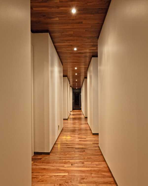 Corridoio interno di un'abitazione in legno con pareti bianche e pavimento in legno