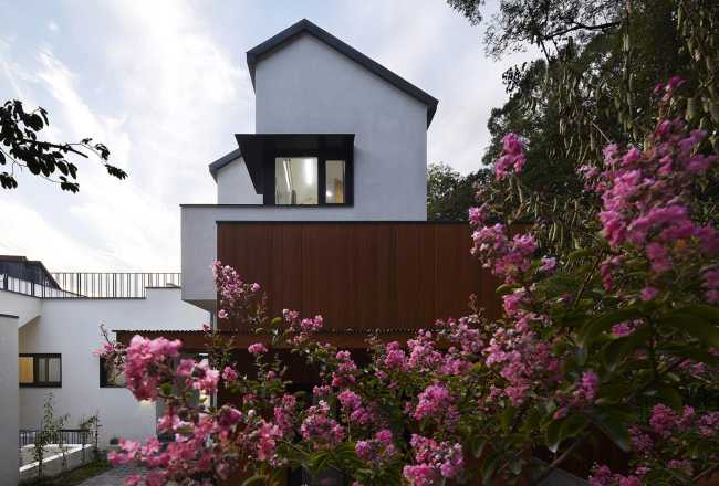 Abitazione in legno con volumi bianchi e legno con fiori
