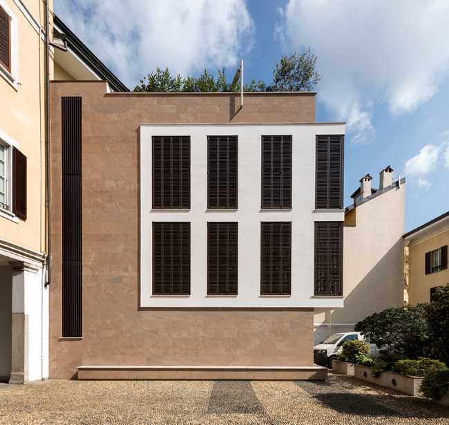 Facciata salmone e bianca con alte finestre e persiane