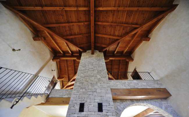 Interior de villa de doble altura en piedra y madera