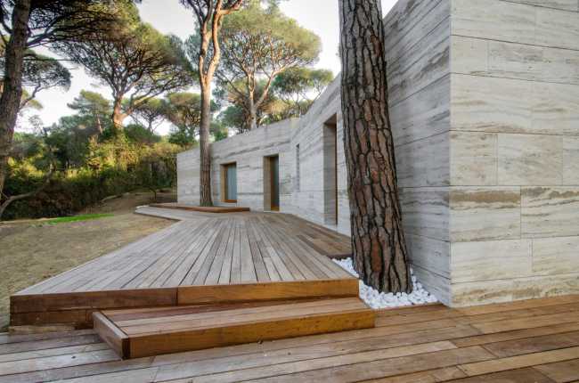 Residencia cubierta en travertino con plataformas de madera frente a la casa