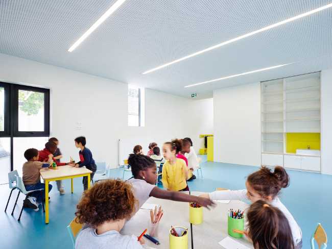 Scuola elementare con tavoli gialli e pavimento azzurro