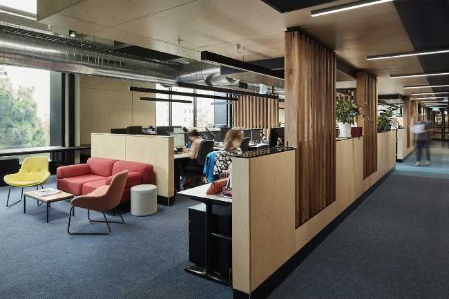 Interni aree studio con scrivanie in legno e divani colorati