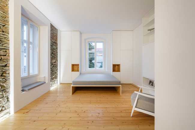 Interior blanco y piedra con parquet y balaustrada de metal