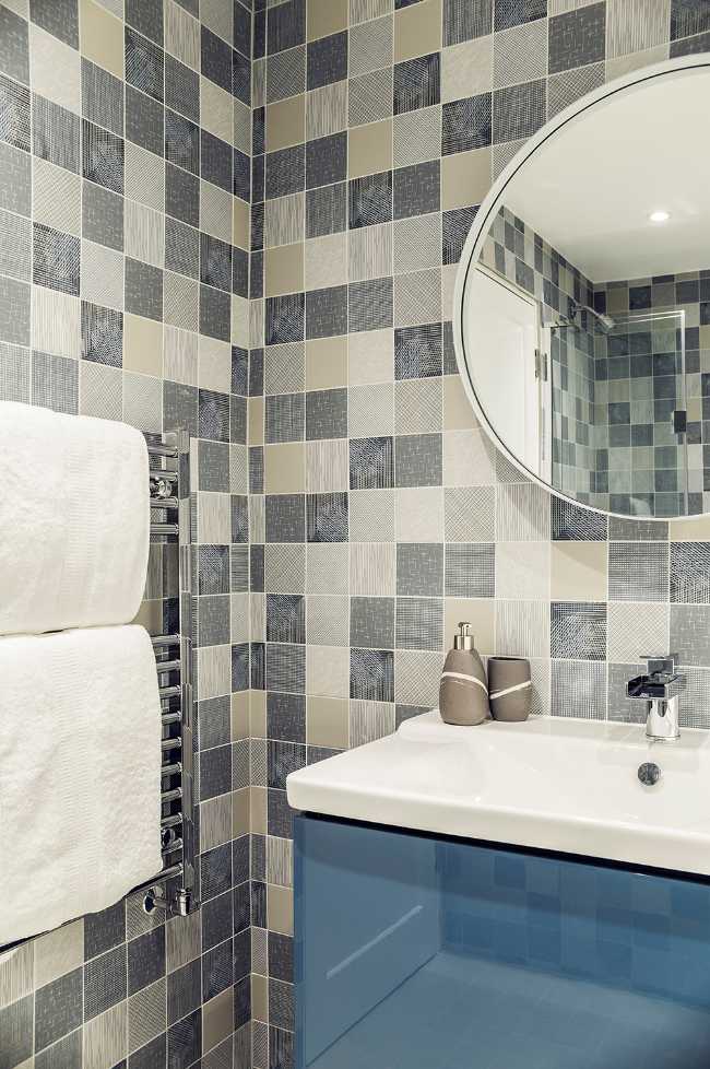 Bagno con piastrelle grigie e bianche e mobile blu