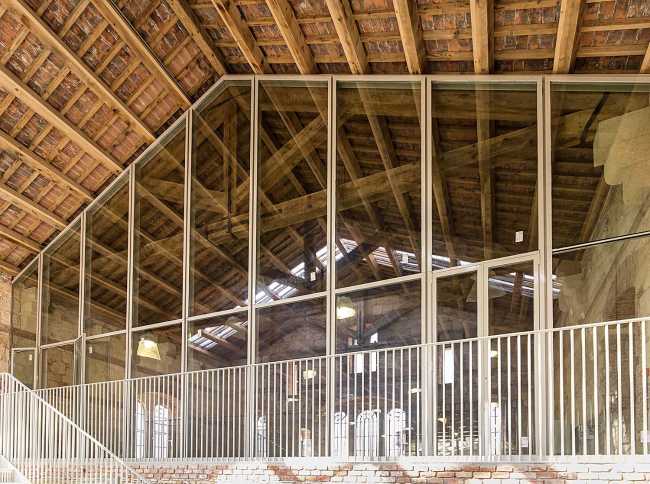 Caserma recuperata con legno, vetro e balaustra in metallo