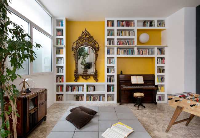 Interno appartamento con parete gialla e libreria