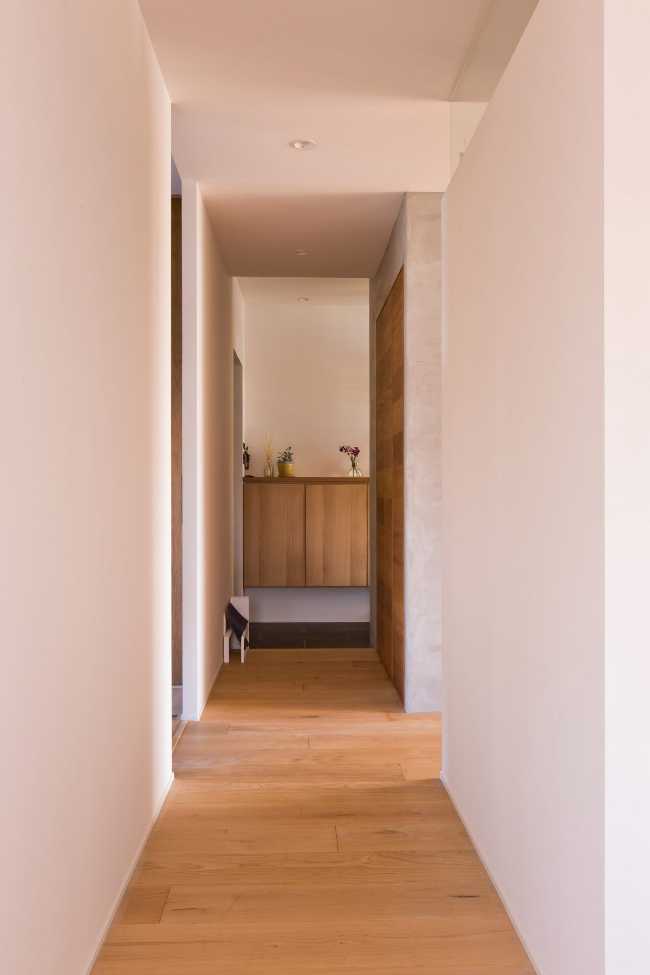 Corridoio con pareti bianche e porte in legno e parquet