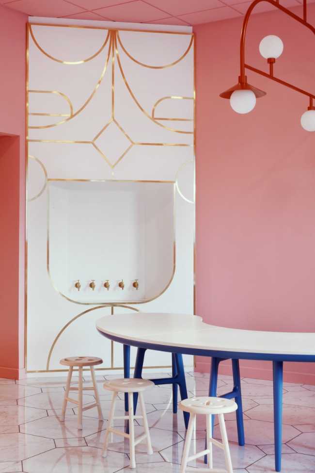 parete rosa e tavolo lungo curvo con gambe blue