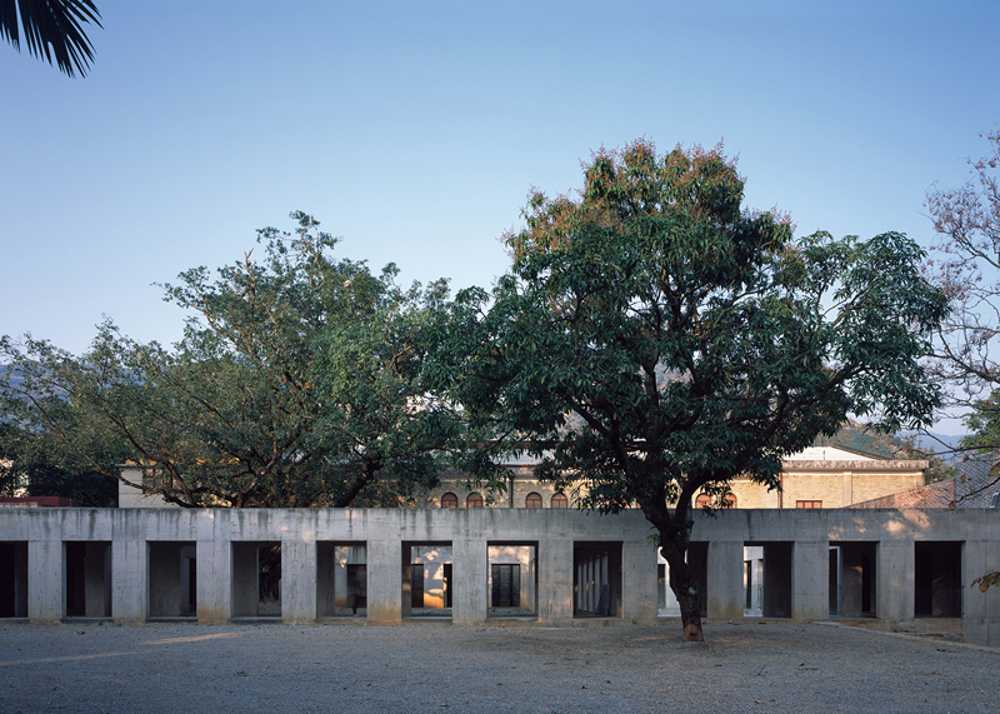 Briques, cours, arbres luxuriants. Rénovation d'un bâtiment datant des années 80
