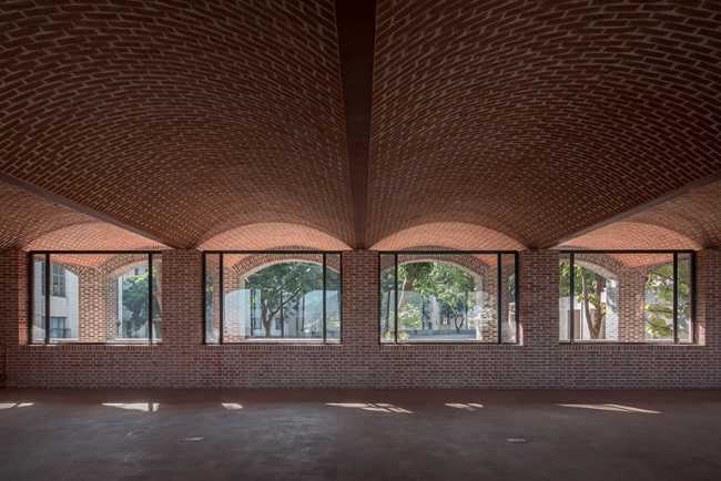 Briques, cours, arbres luxuriants. Rénovation d'un bâtiment datant des années 80