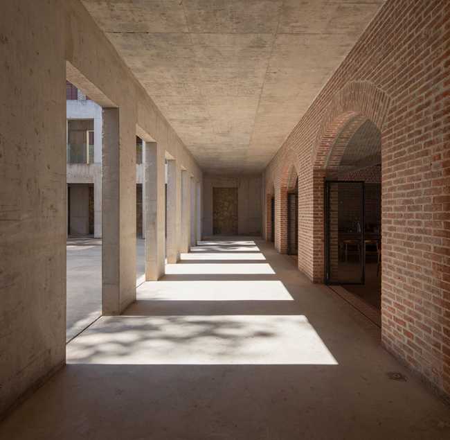 Briques, cours, arbres luxuriants. Rénovation d'un bâtiment datant des années 80