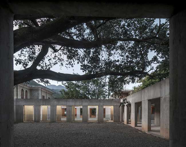 Briques, cours, arbres luxuriants. Rénovation d'un bâtiment datant des années 80