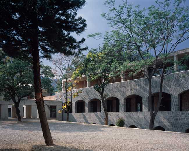 Briques, cours, arbres luxuriants. Rénovation d'un bâtiment datant des années 80
