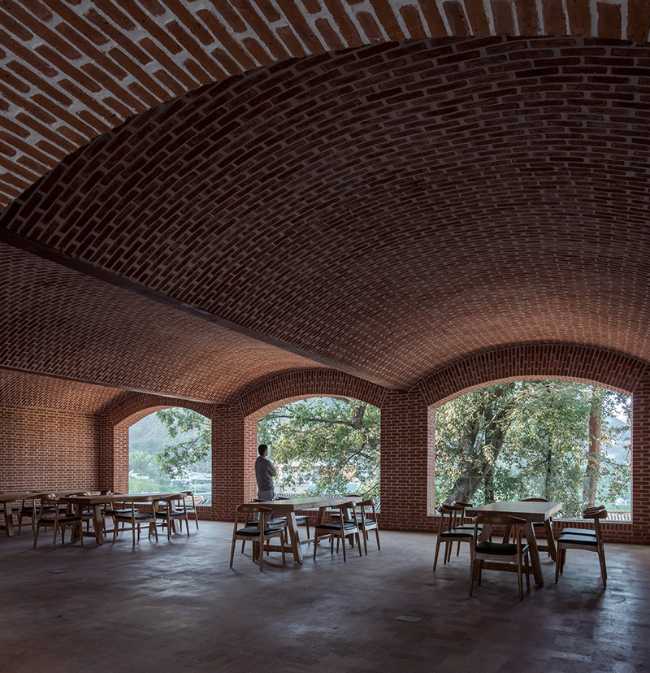 Briques, cours, arbres luxuriants. Rénovation d'un bâtiment datant des années 80