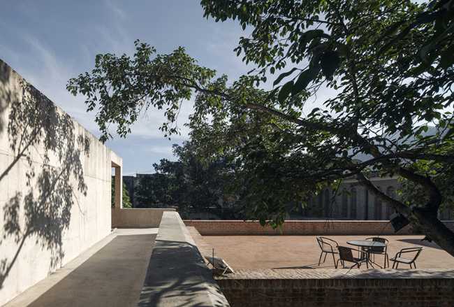 Briques, cours, arbres luxuriants. Rénovation d'un bâtiment datant des années 80