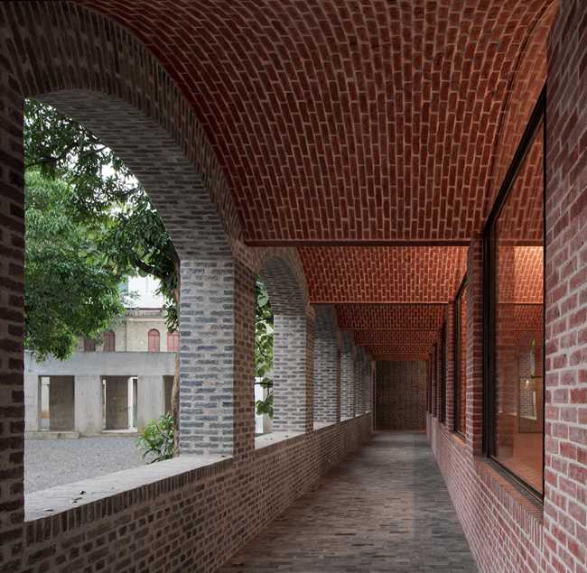 Briques, cours, arbres luxuriants. Rénovation d'un bâtiment datant des années 80