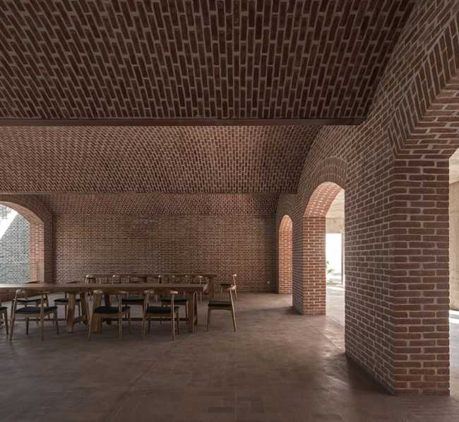 Briques, cours, arbres luxuriants. Rénovation d'un bâtiment datant des années 80