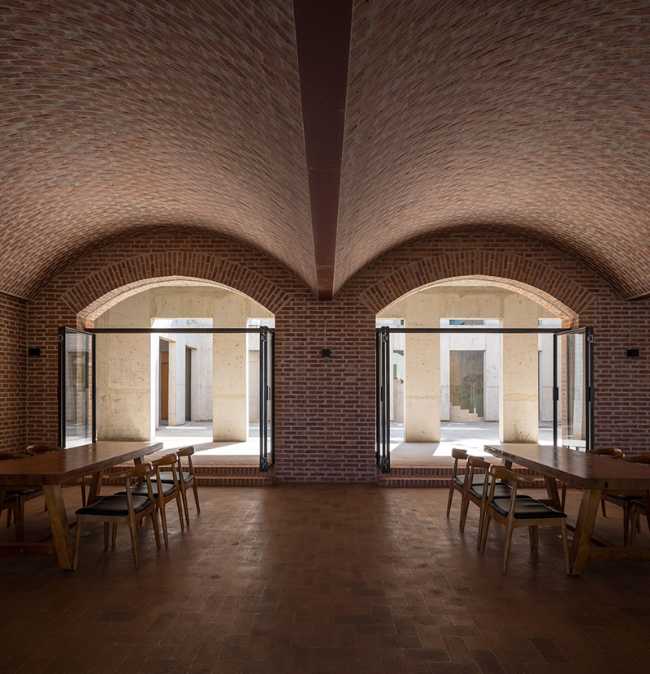 Briques, cours, arbres luxuriants. Rénovation d'un bâtiment datant des années 80