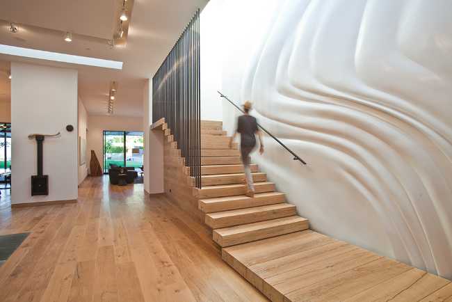 Cuerpo escalera de madera y pared que recuerda el tejido