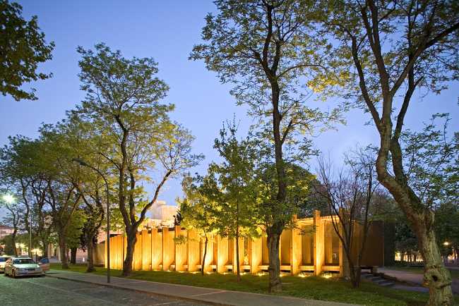 Illuminated wooden pavilion between the trees