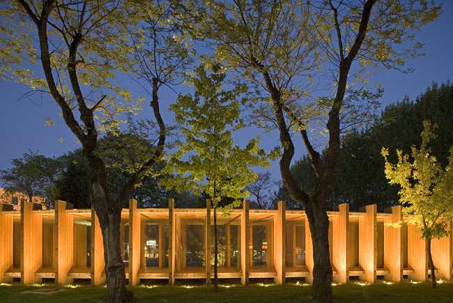 Illuminated wooden pavilion between the trees