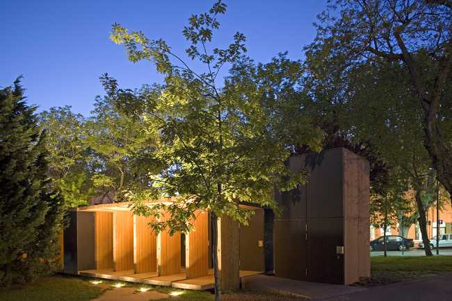 Illuminated wooden pavilion between the trees
