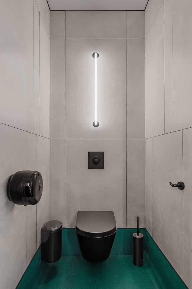 Cuarto de baño con sanitarios negros y suelo verde